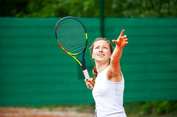 Woman pointing in the sky with tennis racket in hand
